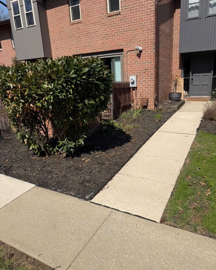 Mulched bed along a brick townhouse with plastic edging